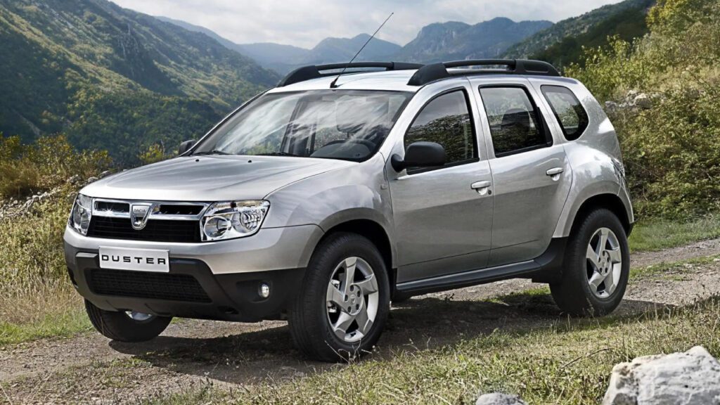 Dacia Duster I, srebrny SUV w terenie, ujęcie z boku