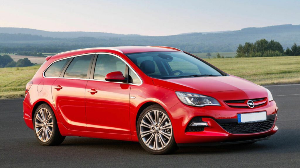 Opel Astra J, czerwony hatchback na tle pola – frontalny kadr